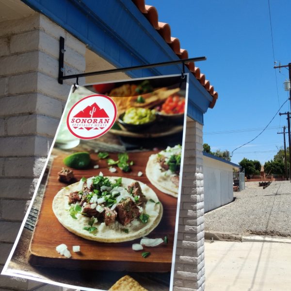 Banner outside the store showing carne asada tacos with the Sonoran Specialty Meats logo